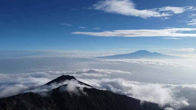 A sweeping aerial view of mountains above a sea of clouds
